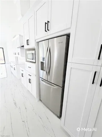 Kitchen featuring a stainless steel French door refrigerator, white shaker-style cabinetry with matte black hardware, and an integrated microwave