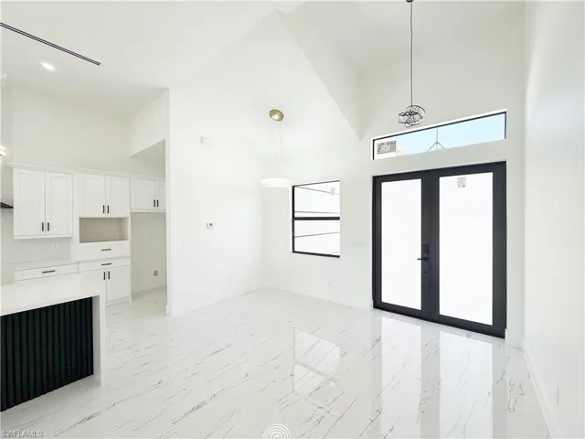 Open-concept living area featuring a vaulted ceiling and white tile flooring