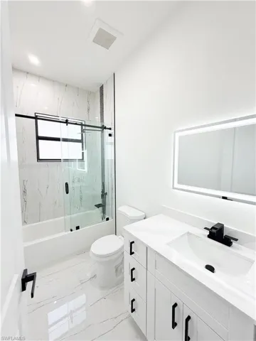 Modern bathroom featuring a white vanity with black hardware, a rectangular undermount sink, and a lighted mirror