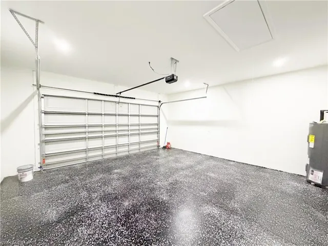 Spacious garage featuring a durable flake epoxy flooring, automatic garage door opener, white painted walls, recessed lighting, and a ceiling-mounted access panel