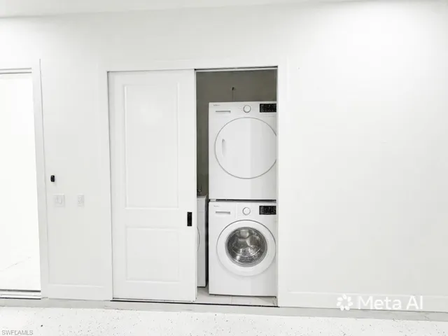 Space-saving laundry closet featuring a stacked washer and dryer unit, white panel barn door, and sleek black hardware