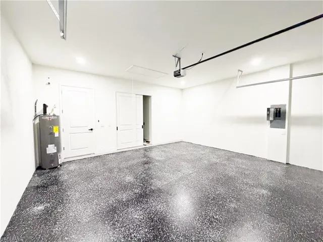 Spacious garage featuring an epoxy-coated floor, bright overhead lighting, and white walls