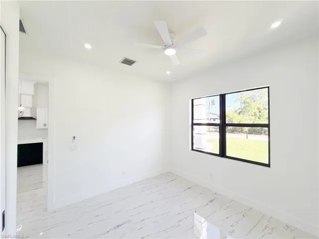 Bright interior featuring large windows with black frames, recessed ceiling lighting, and a modern ceiling fan