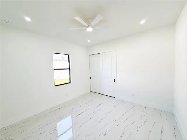 Room featuring white walls, a single window with dark trim, and polished tile flooring with a veined pattern