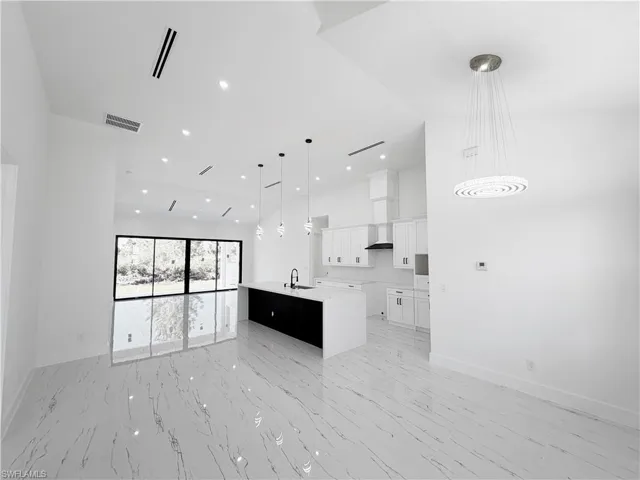 Spacious living area featuring polished tile flooring, recessed lighting, and expansive sliding glass doors