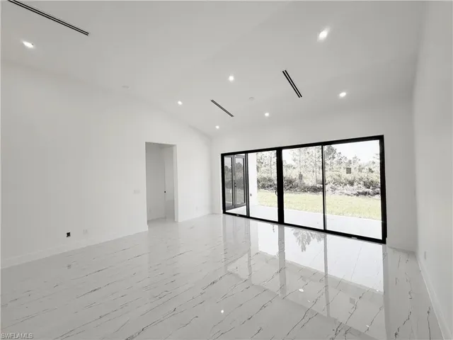 Spacious room featuring vaulted ceilings, recessed lighting, and large sliding glass doors