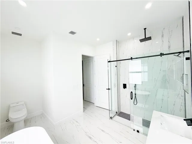 Contemporary bathroom featuring a spacious glass-enclosed shower with black fixtures, overhead rainfall showerhead, and a sliding barn door style entry