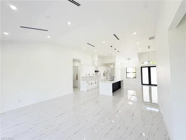 Open-concept living space featuring high ceilings, recessed lighting, and large format tile flooring