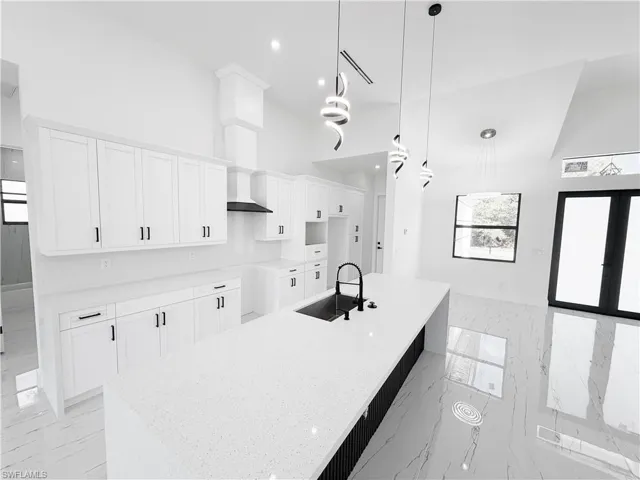 Modern kitchen featuring an extended island with a built-in sink and contemporary pendant lighting