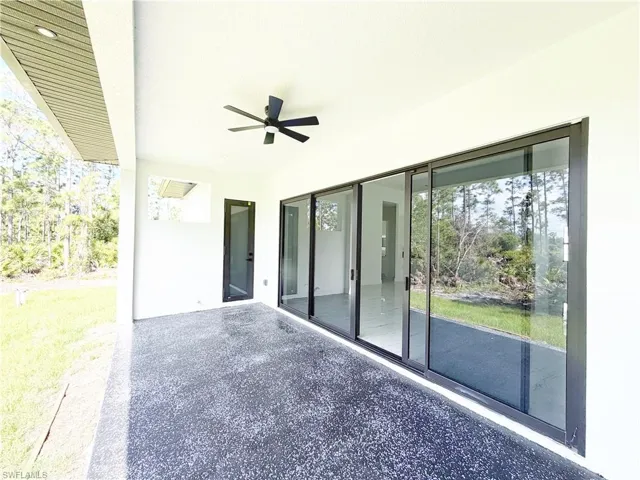 Expansive covered patio featuring a textured concrete surface, a modern ceiling fan, and multiple large sliding glass doors