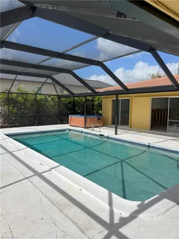 View of swimming pool featuring a hot tub, a patio, and a lanai