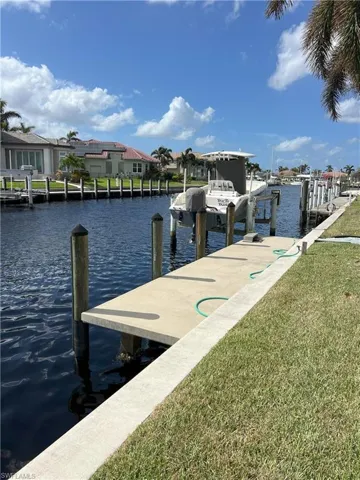 View of dock with a water view and a lawn