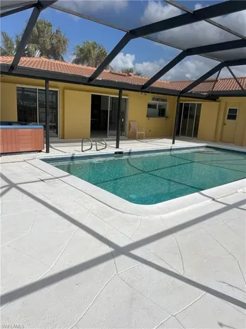 View of swimming pool featuring a hot tub, a patio area, and glass enclosure