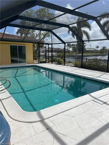View of swimming pool with a patio, a water view, and a lanai