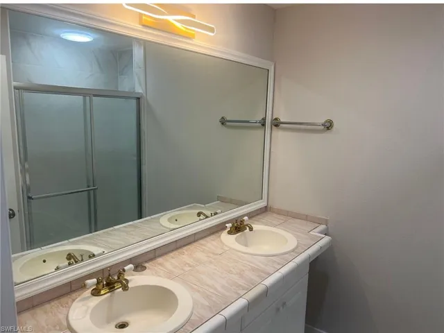 Full bath with double vanity and a stall shower