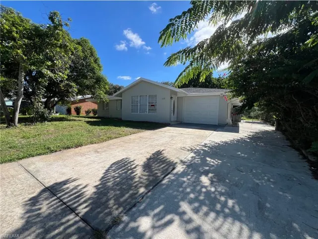 View of front facade featuring concrete driveway, a garage, a front lawn, and stucco siding