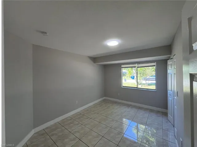 Unfurnished room with light tile patterned floors and baseboards