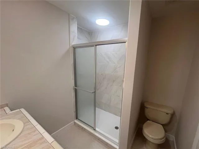 Full bath featuring a stall shower, vanity, and light tile patterned floors