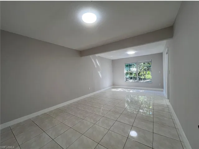Unfurnished room featuring light tile patterned floors and baseboards