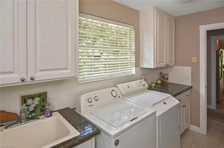 Utility area with white cabinetry, a single basin sink, and granite countertops