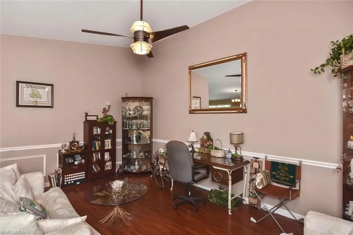 Vaulted ceiling with a contemporary ceiling fan, wood-finish flooring, and crown molding