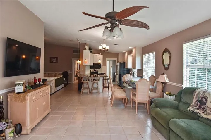 Spacious living area featuring tile flooring, vaulted ceiling, and an open-concept kitchen with a breakfast bar