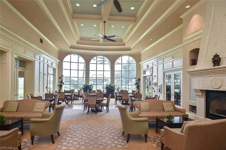 Spacious room featuring multiple arched windows, recessed lighting, a coffered ceiling, and a built-in fireplace
