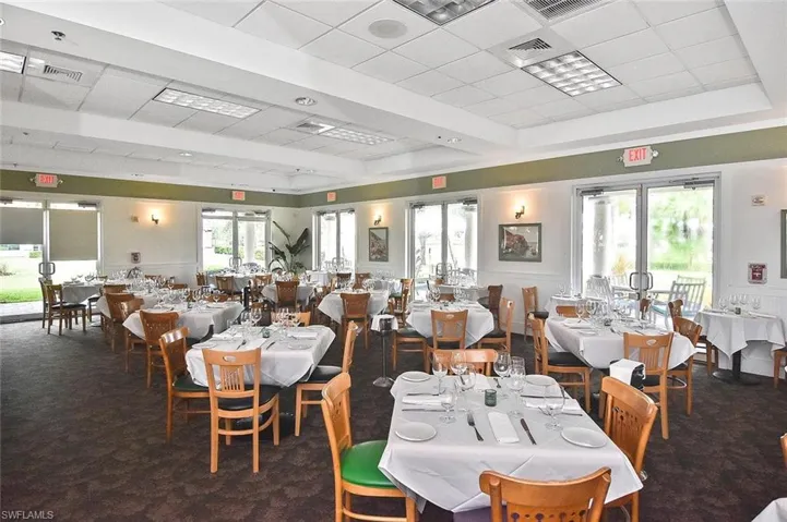 Spacious dining room featuring multiple glass panel doors, wall sconces, recessed lighting, and a textured carpet