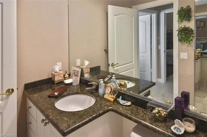 Double vanity with dark stone countertop, undermount sinks, and white cabinetry