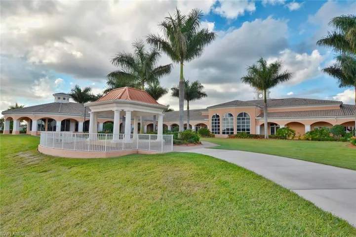 Expansive lawn surrounding a paved walkway, a gazebo with a copper-tone roof, and a large building featuring arched windows and columns