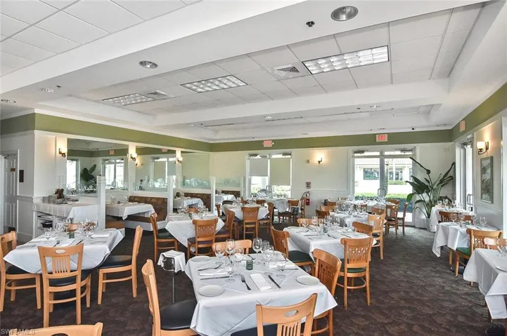 Spacious dining area featuring multiple seating arrangements, recessed ceiling lighting, and expansive windows