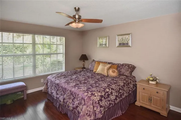 Wood-finish flooring, broad window with horizontal blinds, and a ceiling fan with integrated lighting