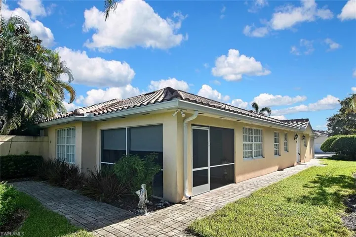 Mediterranean-style exterior featuring a tile roof, stucco finish, screened patio, and a paver walkway