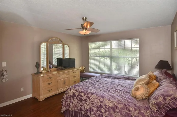 Hardwood-style flooring, window with blinds, ceiling fan with integrated lighting, and neutral wall tones