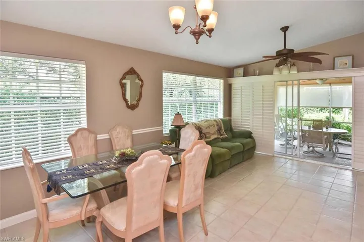 Tiled flooring throughout, multiple windows with horizontal blinds, built-in ceiling fan, light fixture, and sliding glass doors with interior shutters