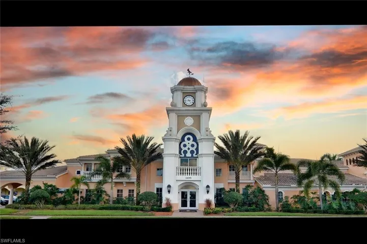 Building facade featuring a prominent clock tower with a dome and weathervane, arched entryway, and surrounding mature palm trees