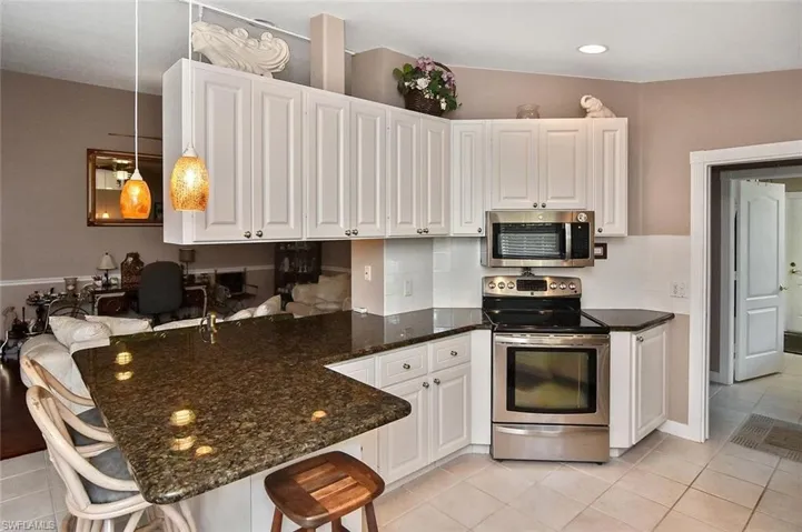 Kitchen featuring white shaker-style cabinetry, dark stone-finish countertops, and stainless steel appliances