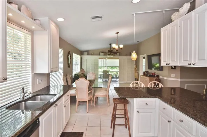 Kitchen featuring white cabinetry, dark stone countertops, a stainless steel double-basin sink, and recessed lighting
