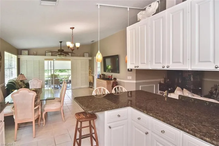 White shaker-style cabinetry, granite countertops, tile flooring, and sliding glass doors with plantation shutters