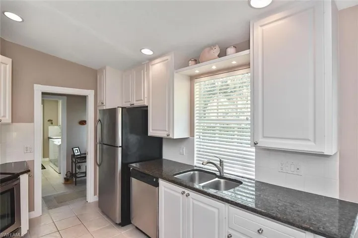 Kitchen featuring white cabinetry, dark stone countertops, stainless steel appliances, a tile backsplash, and recessed lighting