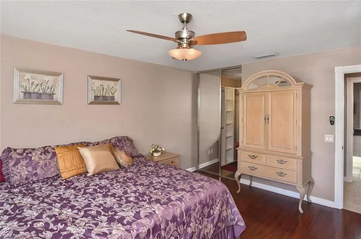 Hardwood-style flooring, ceiling fan with integrated lighting, mirrored sliding closet doors, and light-toned wall finishes