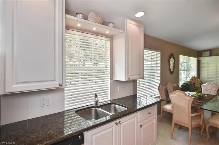 White shaker cabinetry with dark stone countertops, undermount double-basin sink, and recessed lighting