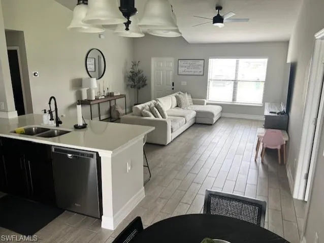 Kitchen with sink, dishwasher, a kitchen breakfast bar, ceiling fan, and light hardwood / wood-style flooring