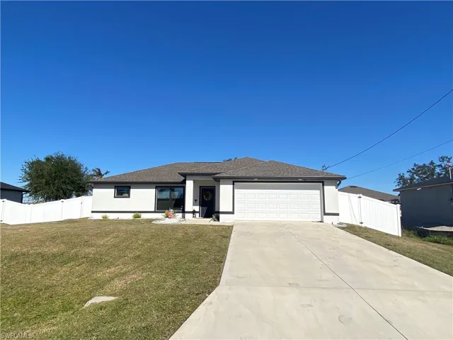 View of front of property with a garage and a front lawn