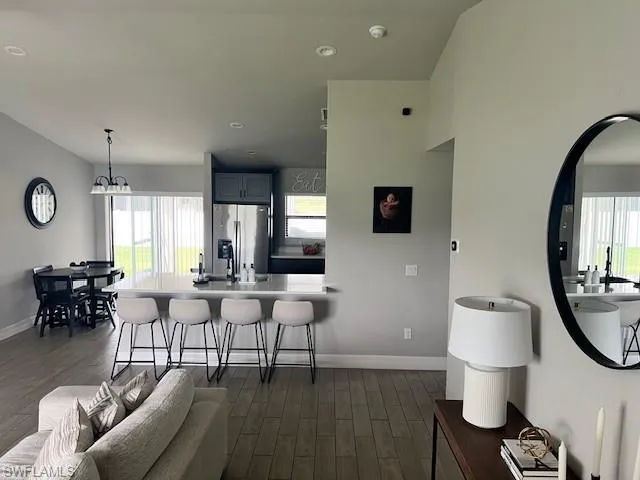 Kitchen featuring a breakfast bar, stainless steel fridge with ice dispenser, a wealth of natural light, and dark hardwood / wood-style floors