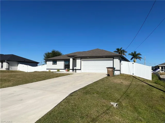 View of front of property featuring a front yard and a garage