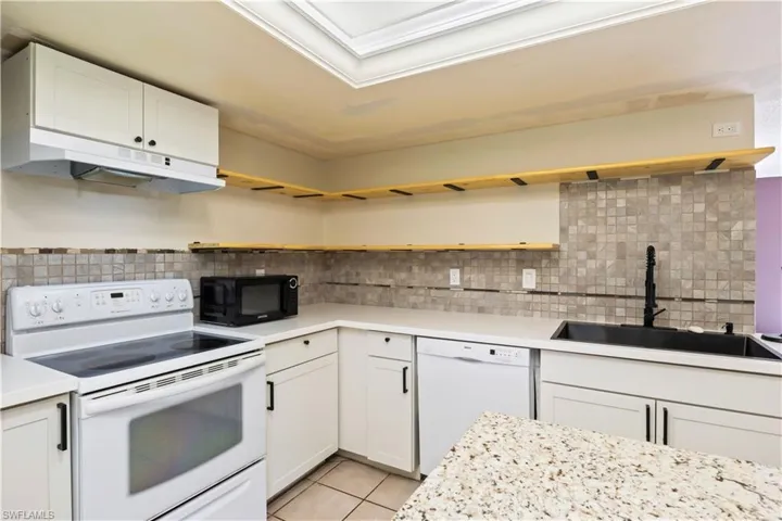 Kitchen featuring open shelves, white appliances, under cabinet range hood, light countertops, and light tile patterned flooring