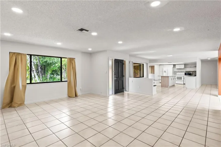 Unfurnished living room with recessed lighting, a textured ceiling, and light tile patterned floors