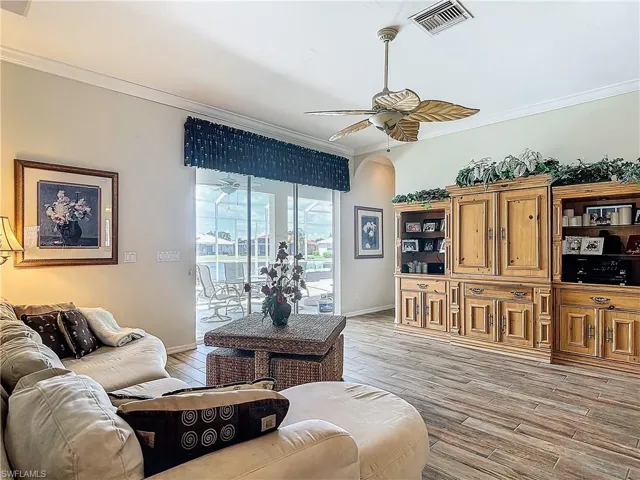 Living room with ceiling fan, ornamental molding, and light hardwood / wood-style floors