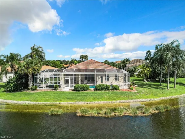 Back of property featuring a lawn, a water view, and glass enclosure
